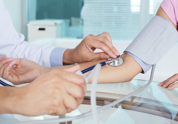 Close-up of patients arm during blood pressure measuring at medical consultation